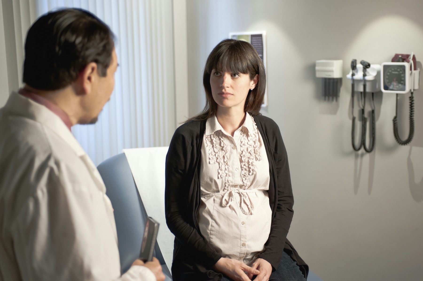 femme enceinte assise en consultation face à un médecin dans un cabinet de gynécologie