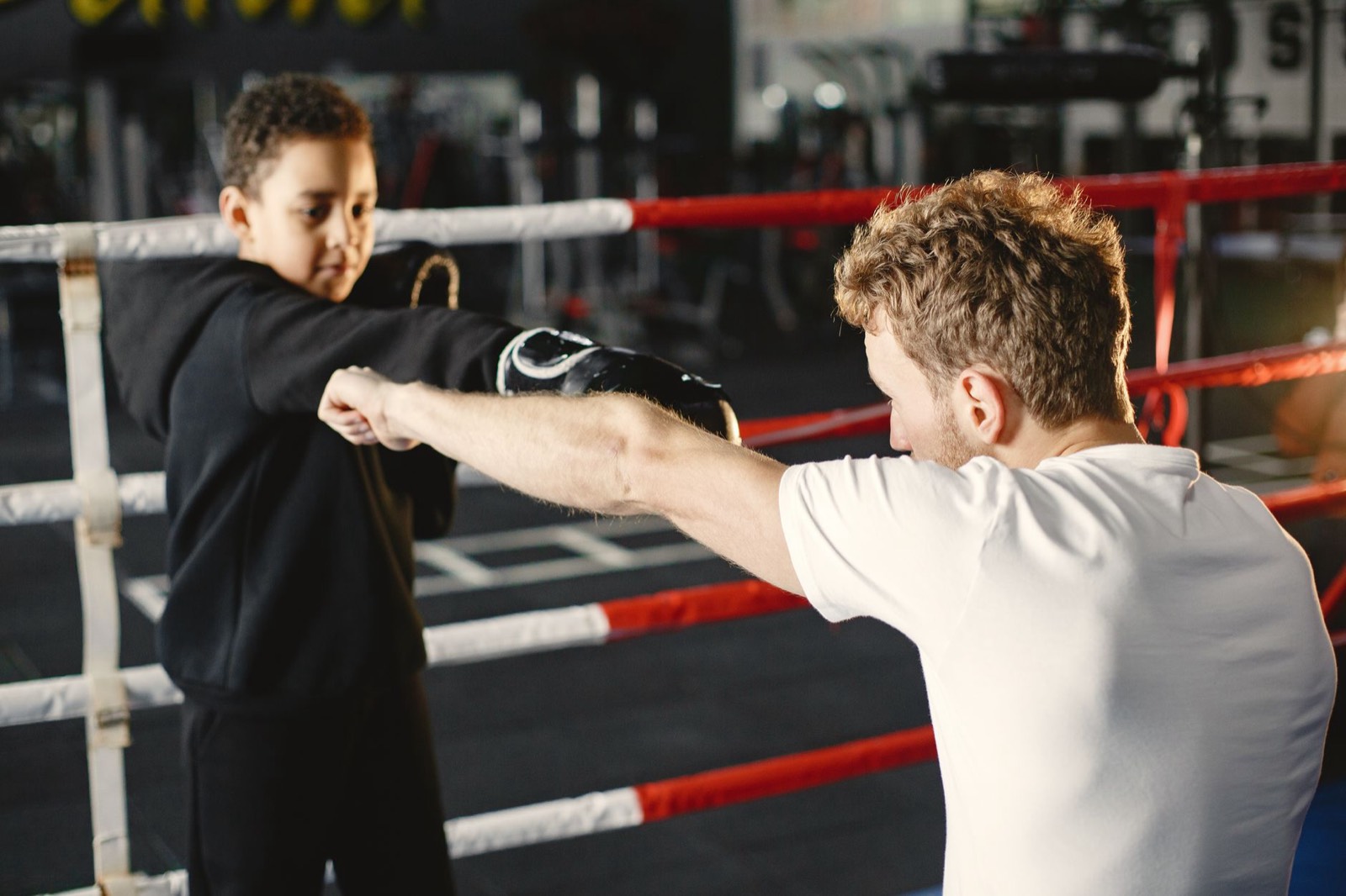 enfant qui se fait mettre des bandes de boxe par un coach